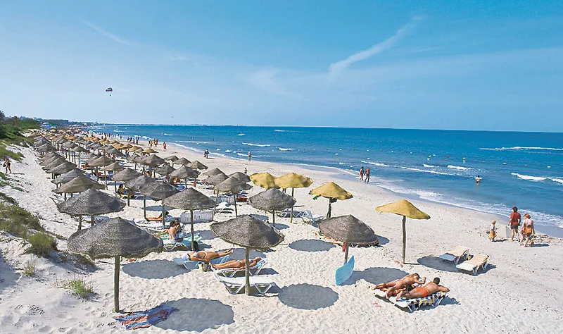 Široka peščena plaža s slamnatimi senčniki