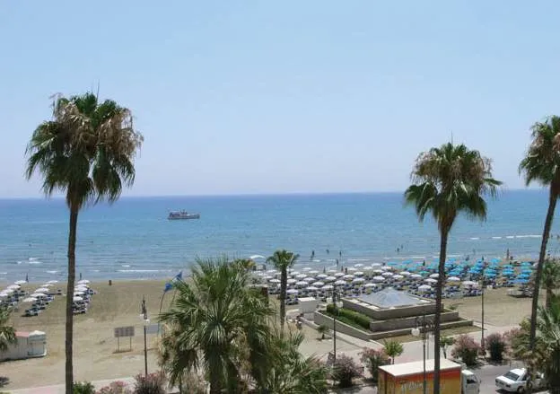 Pogled na peščeno plažo in modro morje pred hotelom