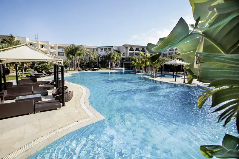 Velik zunanji bazen z modro vodo in ležalniki v hotelu The Russelior